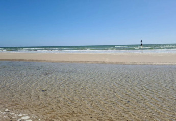 Vue de la plage depuis maison de vacances 6 personnes à Blåvand, Danemark, avec sable et mer.
