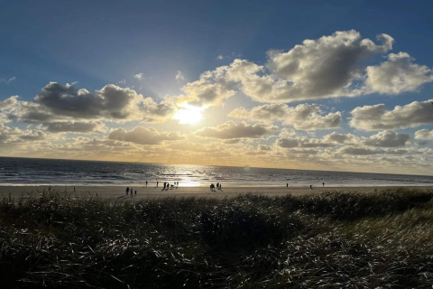 Tramonto sulla spiaggia di Blåvand, Danimarca, visto dalla casa vacanze per 6 persone, con gente sulla sabbia.