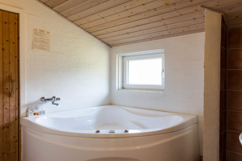 Hoekbad onder schuin houten plafond in '6-persoons vakantiehuis in Blåvand' in Denemarken.
