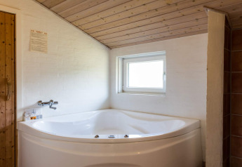 Eckbadewanne unter einer Holzdecke im '6 Personen Ferienhaus in Blåvand' in Dänemark.