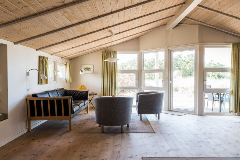 Helles Wohnzimmer mit Holzbalkendecke, großen Fenstern und skandinavischem Design in Blåvand, Dänemark.