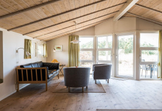 Helles Wohnzimmer mit Holzbalkendecke, großen Fenstern und skandinavischem Design in Blåvand, Dänemark.