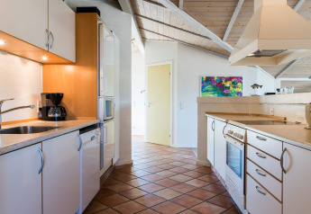 Cuisine moderne d'une maison de vacances à Blåvand, Danemark, avec placards blancs et tableau coloré.