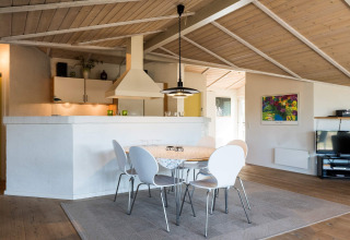 Helles Esszimmer und Küche in einer modernen Lodge in Blåvand, Dänemark mit Holzdecke.