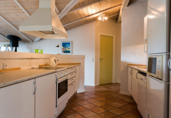 Moderne keuken in een vakantiehuis in Blåvand, Denemarken, met witte kasten en houten plafond.