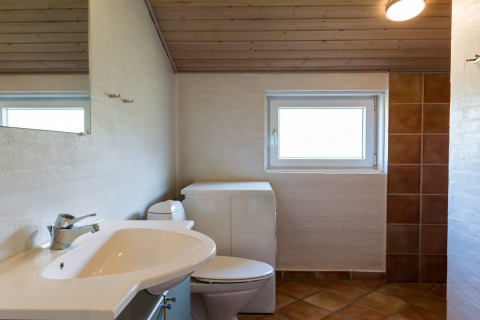 Modernes Badezimmer mit Waschbecken, Toilette und Fenster im 6-Personen-Ferienhaus in Blåvand, Dänemark.