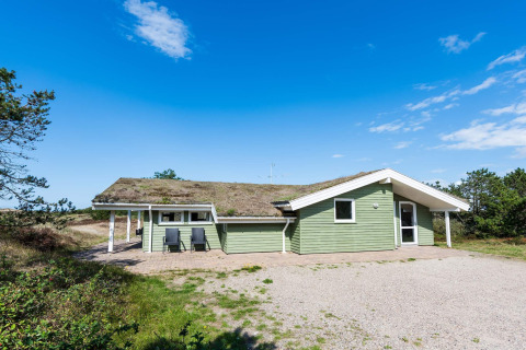 Vakantiehuis voor 6 personen met grasdak in Blåvand, Denemarken, omgeven door natuur en blauwe lucht.