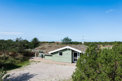 Casa vacanze verde chiaro a Blåvand, Danimarca, circondata dalla natura con cielo azzurro limpido.