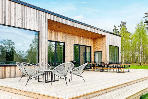 Udendørs terrasse på Cozy Sea House med moderne havemøbler og udsigt til skov og natur.