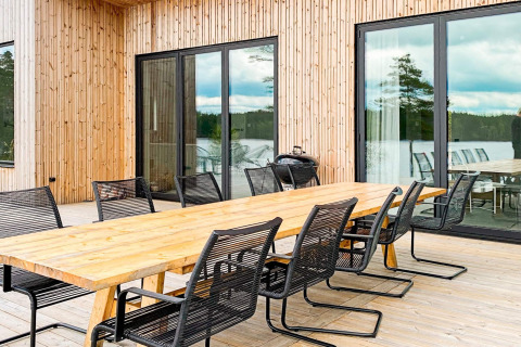 Udendørs spiseområde med langt træbord og sorte stole ved lodge 'Cozy Sea House with Guest Cottage' i Sverige.