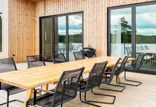 Udendørs spiseområde med langt træbord og sorte stole ved lodge 'Cozy Sea House with Guest Cottage' i Sverige.
