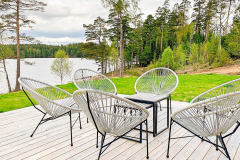 Udendørs terrasse med moderne stole ved sø og skov, Cozy Sea House med gæstehus i Sverige.
