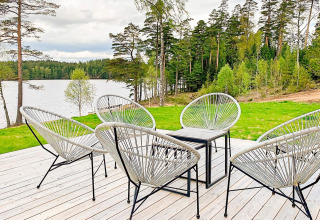 Udendørs terrasse med moderne stole ved sø og skov, Cozy Sea House med gæstehus i Sverige.