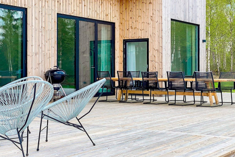 Udendørs terrasse ved Cozy Sea House i Sverige med moderne havemøbler, grill og store vinduer.