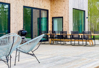 Udendørs terrasse ved Cozy Sea House i Sverige med moderne havemøbler, grill og store vinduer.