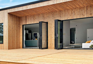 Udendørs udsigt over Cozy Sea House med gæstehytte i Sverige, moderne træfacade og store glasdøre.