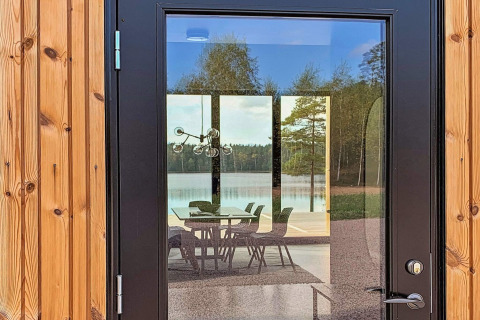 Refleksion af en søudsigt og et spisebord set gennem døren på Cozy Sea House med Guest Cottage i Sverige.