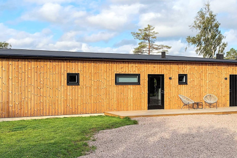 Udendørsbillede af Cozy Sea House med gæstehytte i Sverige, moderne træfacade og afslappet terrasse.