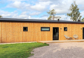 Udendørsbillede af Cozy Sea House med gæstehytte i Sverige, moderne træfacade og afslappet terrasse.