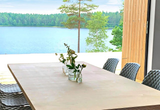 Spisebord med blomster og udsigt over en sø og skov ved Cozy Sea House med gæstehytte i Sverige.