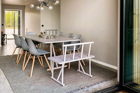 Spisestue i moderne lodge ved navn Cozy Sea House med stilfulde stole, bænk og store vinduer i Sverige.