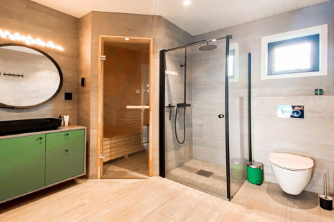 Moderne badeværelse i Cozy Sea House med sauna, bruser, toilet og grøn kommode i Sverige.