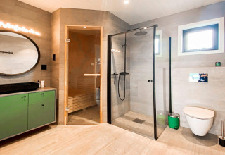 Moderne badeværelse i Cozy Sea House med sauna, bruser, toilet og grøn kommode i Sverige.