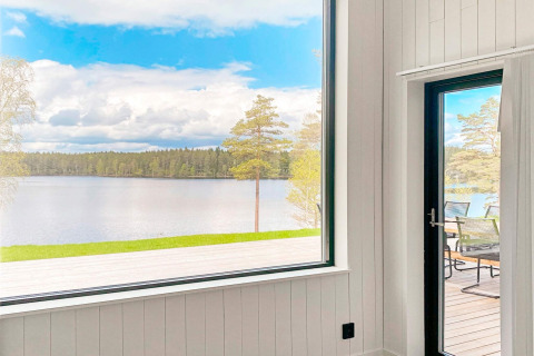Udsigt fra Cozy Sea House med gæstehytte i Sverige, med panoramaudsigt over sø og skov fra stuen.