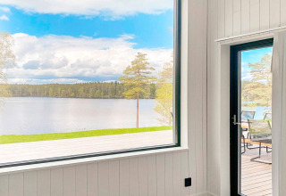 Udsigt fra Cozy Sea House med gæstehytte i Sverige, med panoramaudsigt over sø og skov fra stuen.