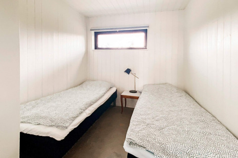 Et enkelt, lyst værelse med to enkeltsenge i Cozy Sea House med gæstehytte i Sverige, minimalistisk stil.