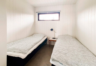 Et enkelt, lyst værelse med to enkeltsenge i Cozy Sea House med gæstehytte i Sverige, minimalistisk stil.