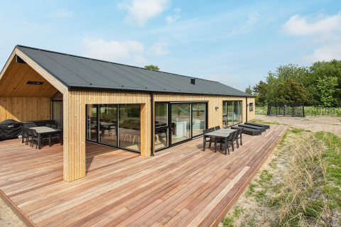Casa vacanze moderna a Sæby, Danimarca, con rivestimento in legno, ampia terrazza e mobili da esterno.
