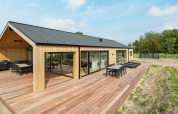 Casa de vacaciones moderna en Sæby, Dinamarca, con revestimiento de madera, amplia terraza y muebles de jardín.