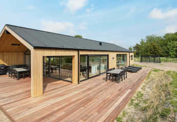 Moderne vakantiewoning in Sæby, Denemarken, met houten bekleding, groot terras en buitenmeubilair.
