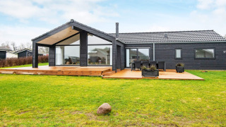 Buitenzicht op een 8-persoons vakantiewoning in Sydals met zwart hout en een groot terras op de tuin.