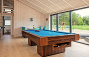 Table de billard dans un salon lumineux avec grandes baies vitrées, vue nature, maison de vacances Sæby.