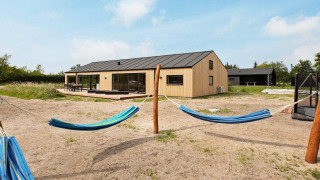 Vista esterna di una casa vacanze moderna per 10 persone a Sæby, con amache e giardino sabbioso.