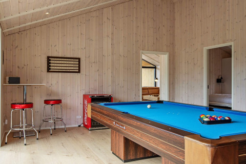 Salle de jeux dans maison de vacances à Sæby, Danemark, avec billard bleu et tabourets de bar rouges.