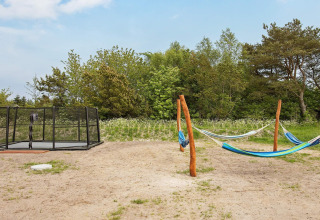 Area giochi esterna presso casa vacanze a Sæby, Danimarca, con amache e trampolino immersi nel verde.