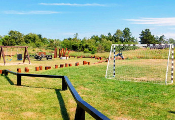 Aire de jeux extérieure avec cage de foot, balançoires, table de pique-nique et rondins à Sæby, Danemark.
