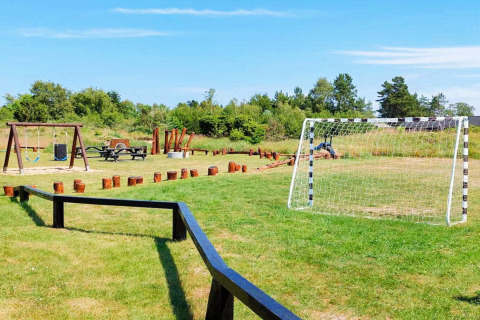Buitenspeelplaats met voetbaldoel, schommels, picknicktafel en boomstammen bij vakantiehuis Sæby, Denemarken.