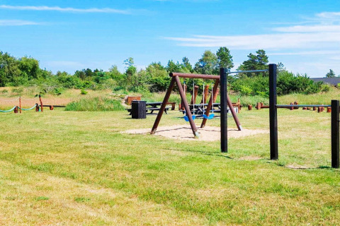 Spielplatz mit Schaukeln und Picknicktischen am 10-Personen-Ferienhaus in Sæby, Dänemark, im Grünen.