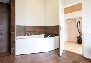 Bagno moderno con vasca e armadio aperto in una casa vacanze per 10 persone a Sæby, Danimarca.