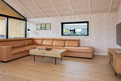 Soggiorno moderno in lodge a Sæby, Danimarca, con divano in pelle e arredi in legno chiaro.