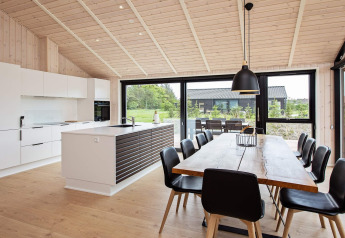 Cocina y comedor modernos en casa de vacaciones para 10 personas en Sæby, Dinamarca, con ventanas grandes.