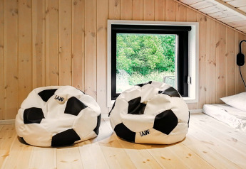Deux poufs ballon de football dans une pièce en bois clair au lodge 10 person holiday home in Sæby, Danemark.