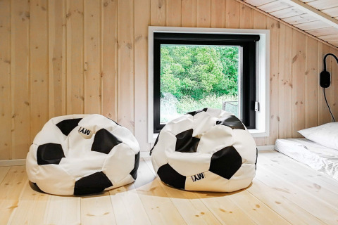 Zwei Fußball-Sitzsäcke in einem hellen Holzraum mit Fenster im 10-Personen-Ferienhaus in Sæby, Dänemark.