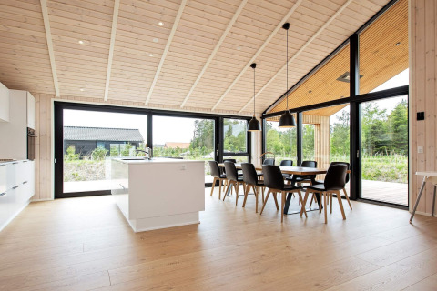 Modernes Ferienhaus in Sæby, Dänemark, mit heller Küche und Essbereich sowie Panoramablick auf die Natur.