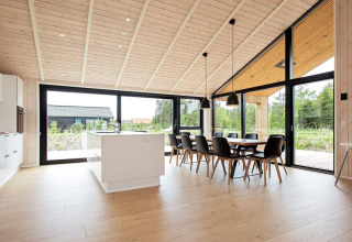 Cocina y comedor modernos con grandes ventanales en casa de vacaciones para 10 personas en Sæby, Dinamarca.