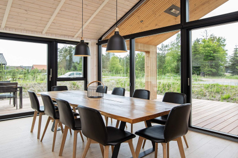 Zona pranzo moderna in una casa vacanze a Sæby, Danimarca, con tavolo in legno e ampie finestre.